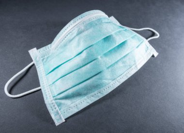 Tek kullanımlık maske, COVID-19 Coronavirus 'a karşı korunmak için cerrahi maske. Koyu gri veya siyah renkte izole edilmiş.