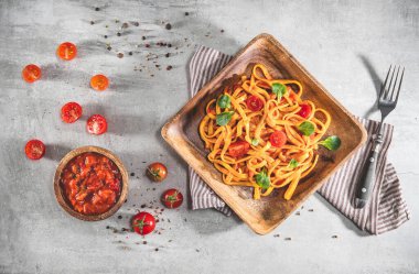 Tabakta domates soslu makarna. Gri masada leziz bir porsiyon tagliatelle servis edildi. Üst görünüm