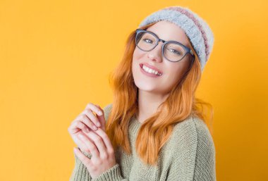 Neşeli genç bir kadın günlük kıyafetler giyer. Gülümseyen güzel kız. Mutluluk. Sarı arka planda izole edilmiş. Stüdyo çekimi