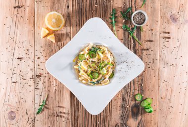 Ekşi kremalı makarna tabağı ve tahta tahtalarda otlar. Üst görünüm