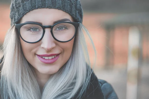 Happy woman face looking to camera, winter day outdoors. Closeup cheerful girl in warm clothing. Female person in cold weather.