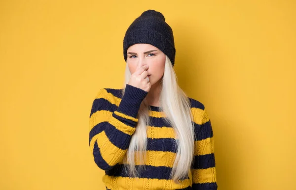 불만을 여자는 얼굴에 구역질 표정을 노란색 배경에는 모자를 스웨터를 모델이다 — 스톡 사진