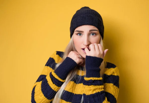 害怕的年轻女人咬指甲 这是可怕的意外 模特头戴羊毛帽和毛衣 孤立在黄色背景 吓坏了的女孩 工作室拍摄 — 图库照片