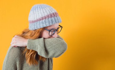 Hapşıran, alerjisi olan, sarı arka planda izole edilmiş genç bir kadın. Stüdyo çekimi