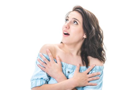 Minnettar genç bir kadın elini göğsüne koyup beyaz arka planda izole bir şekilde yukarı bakıyor. Neşeli dişiler başarıyı kutlar. Stüdyo çekimi