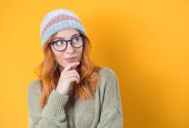 Genç bir kadın hayal gücüyle yukarı bakıyor. Sarı arka planda izole edilmiş, gülen yüz ifadeli kararlı bir şekilde ilham veren kadının yakın plan portresi. İyi bir fikri olan bir kadın. Stüdyo çekimi