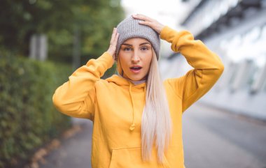 Elleri başının üstünde şaşkın mutlu bir kız. Açık havada gün ışığı. Olumlu haber. Kendinden geçmiş güzel bir kadın. Dışarıda.