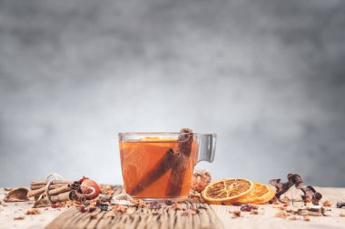 Tarçınlı, portakallı ve böğürtlenli cam fincanda meyve çayı, ahşap masada çay fincanı. Reklamınız ya da mesajınız için boş bir alan. Kopyalama alanı.
