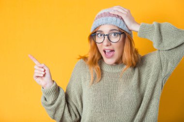 Sarı arka planda izole edilmiş mesajınız ya da resminiz için işaret parmağıyla işaret eden şaşırmış genç bir kadın. Biliyorum, bu sır açığa çıktı. Stüdyo çekimi