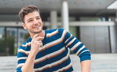 Gülümseyen ve dışarıda poz veren genç bir adam. Moda adamı portresi
