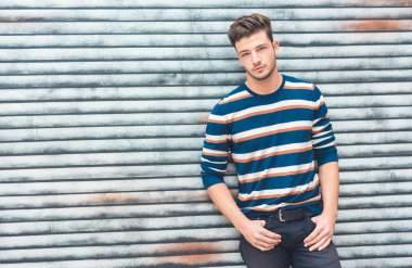 Şehir duvarına karşı ceplerinde el ele tutuşan genç ve güzel bir adamın portresi, kopyalama alanı.