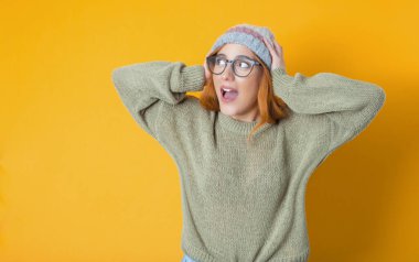 Şaşırmış kadın, sarı arka planda izole edilmiş. Elleri kafasında şaşırmış bir kız. Şaşırtma konsepti. Stüdyo çekimi