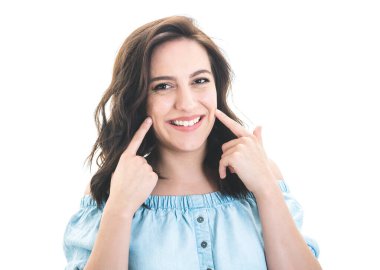 Gülümse genç kadın, beyaz arka planda izole edilmiş yanaklarını ve dişlerini gösteriyor. Gülümseyen güzel kız el hareketi yapıyor. Stüdyo çekimi