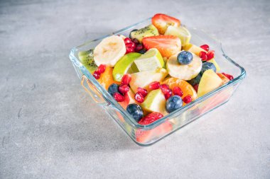 Gri yüzeyde bir kasede meyve salatası ve fotokopi odası manzarası