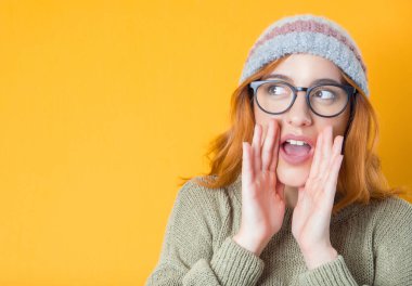 Sarı arka planda izole edilmiş genç bir kadın bağırıyor. Elleri havada mutlu bir kız. Stüdyo çekimi