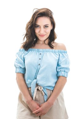 Güzel bir kadın, elleri ceplerinde kameraya bakarken beyaz arka planda izole bir şekilde dikiliyor. Çekici bir kız. Stüdyo çekimi