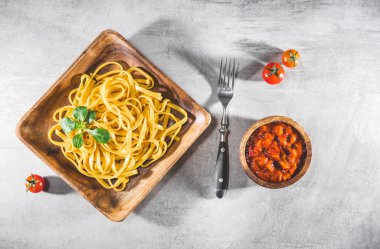 Tabakta domates soslu makarna. Gri masada leziz bir porsiyon tagliatelle servis edildi. Üst görünüm