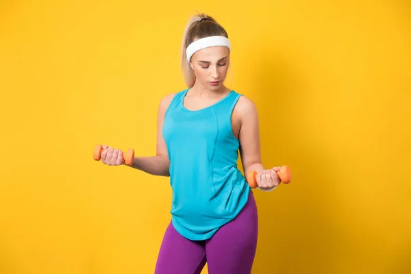 Sportliches Mädchen Trainiert Bizepsmuskel Mit Kurzhantel Isoliert Auf Gelbem Hintergrund lizenzfreie Stockbilder