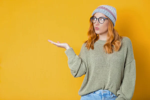 Woman holding free advertising space for your product on his palm, isolated on yellow background. Studio shot