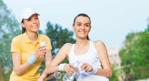 Fröhliche Freundinnen in Sportkleidung trinken Wasser, — Stockfoto