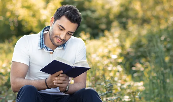 Student reading book in a park. Relaxed man holding book — Stock Photo, Image