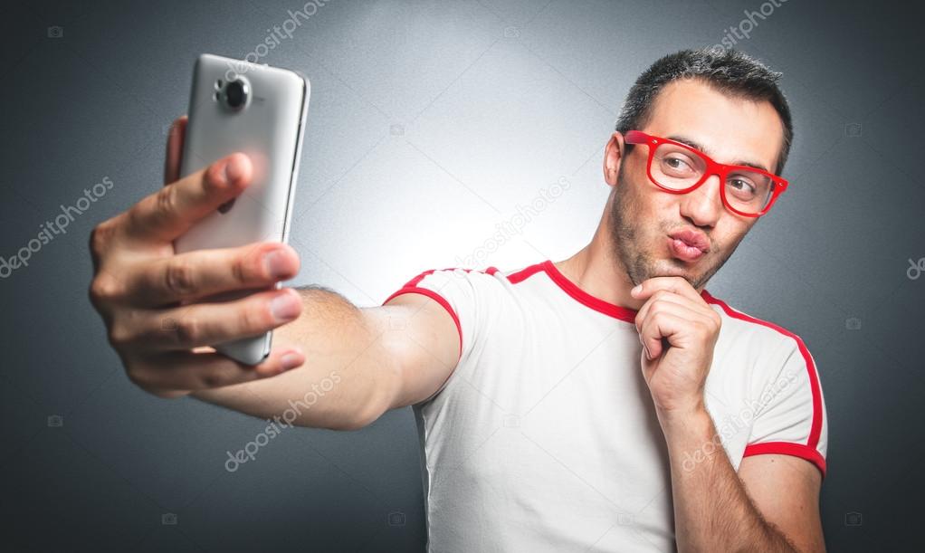 freak guy with pursed lips taking a selfie photo over dark gray