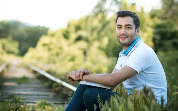 Man sitting on train lines in forest — Stock Photo, Image