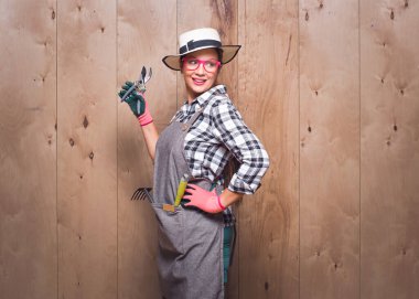 Güzel bahçıvan kadın elinde budama makası ile stüdyoda ahşap arka planda poz veriyor. Taraf tutan güzel bir kadın çiftçi. Uzayı kopyala Stüdyo çekimi