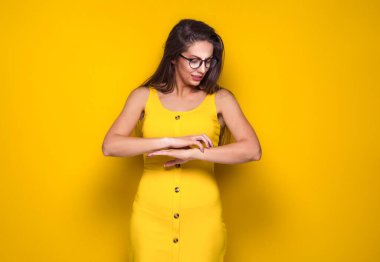 Alerjisi var, kadın elini tırnaklarıyla kaşıyor. Dişi kırmızı deri, diyatez ya da alerji belirtileri, sarı arka planda izole edilmiş. Kırmızılık ve soyulma. Stüdyo çekimi