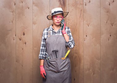 Sinirli bahçıvan kadın telefonda stüdyoda ahşap arka planda. Sinir bozucu kadın konuşması. Baş belası ve akıllı telefon. Stüdyo çekimi