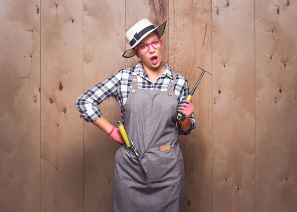 Stüdyoda ahşap arka planda kıskanç bahçıvan kadın. Kızgın kadın çiftçi. Stüdyo çekimi