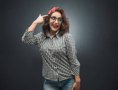 Komik kadın sinagogda parmak tabancası hareketi yapıyor. Koyu gri arka planda intihar ediyormuş gibi yapıyor. Dilini çıkaran aptal kız. Stüdyo çekimi