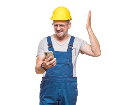 Öfkeli inşaat işçisi, beyaz arka planda izole edilmiş cep telefonuyla konuşuyor. Elinde bozuk akıllı telefon tutan öfkeli tamirci, bir sorun var, sorun var. Stüdyo çekimi