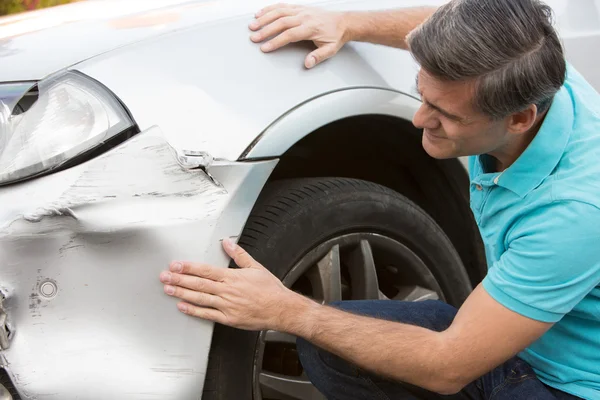 Tyytymätön kuljettaja tarkastaa vahingot auto-onnettomuuden jälkeen — kuvapankkivalokuva