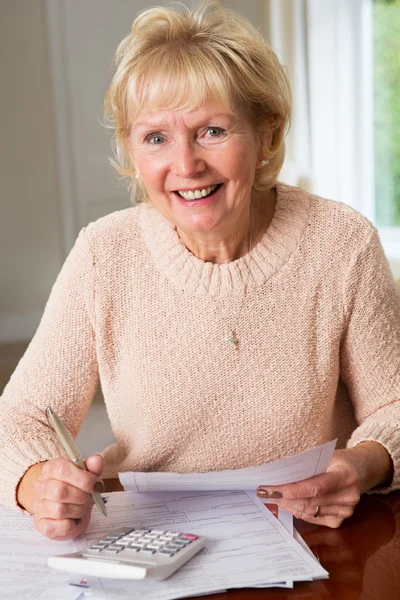 Femme âgée souriante examinant les finances domestiques — Photo