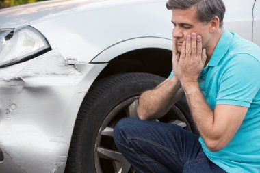 Mutsuz sürücü araba kazasından sonra hasar inceleniyor