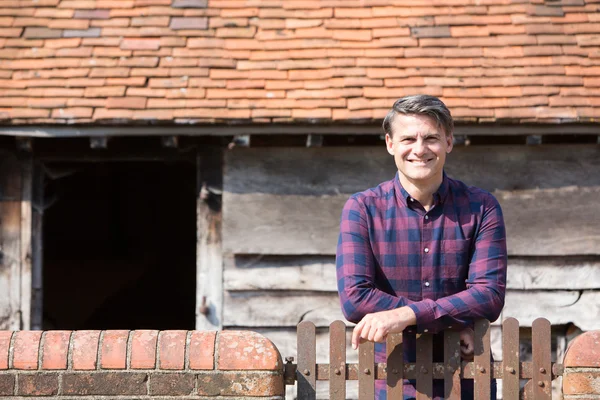 Portrait Of Farmer Looking Over Wall Of Farm Building