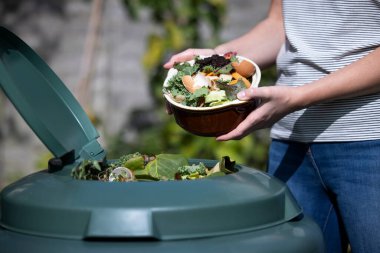 Close Up Of Woman Emptying Food Waste Into Garden Composter At Home clipart