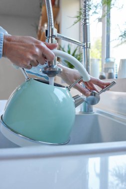 Close Up Of Woman Carefully Filling Kettle From Tap And Saving Water clipart