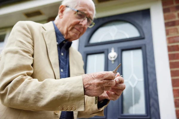 Confused Senior Man With Early Stage Dementia Trying To Find Correct Door Key Outside House