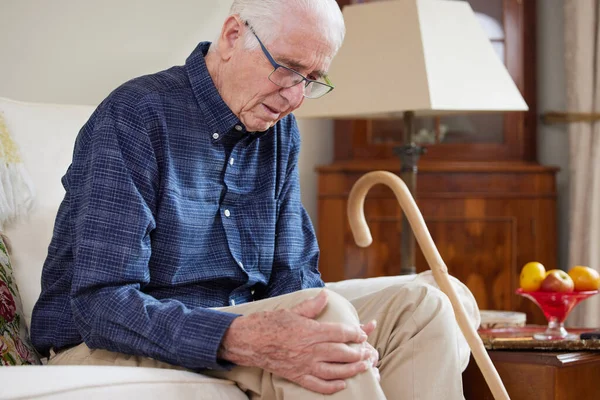 Senior Man Zit Bank Thuis Lijden Met Kniepijn Van Artritis — Stockfoto