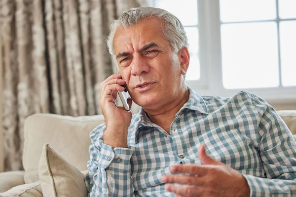 Разочарованный Пожилой Человек Получает Нежелательный Телефонный Звонок Дома — стоковое фото