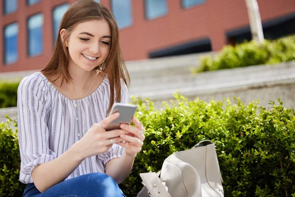 Sorrindo Jovem Mulher Com Telefone Celular Verificando Mídias Sociais Fora — Fotografia de Stock