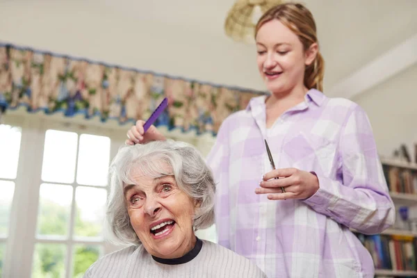 Female Mobile Hairdresser Cutting Senior Womans Hair At Home