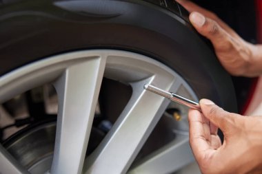 Otomobil lastiği basıncını göstergeyle ölçen adama yakın çekim