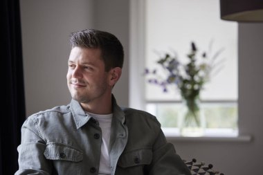 Düşünceli ve hoşgörülü bir adam evde oturup pencereden dışarı bakıyor.