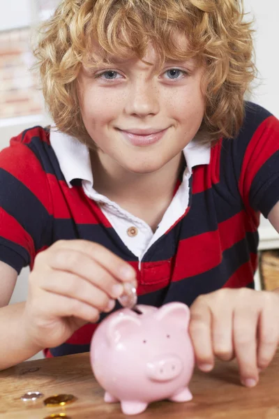 Niño poniendo monedas en alcancía — Foto de Stock