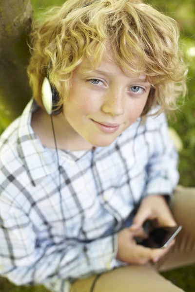 Niño escuchando reproductor de MP3 al aire libre — Foto de Stock