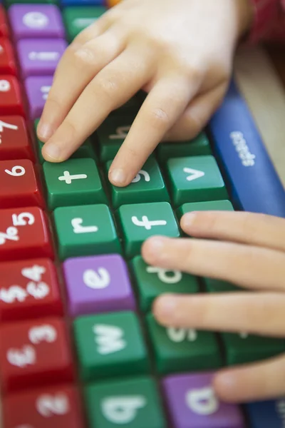 Main de l'enfant tapant sur clavier d'ordinateur coloré — Photo
