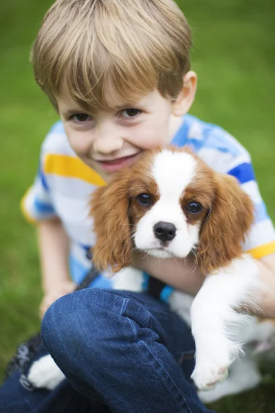 Niño con mascota rey Carlos Spaniel cachorro — Foto de Stock